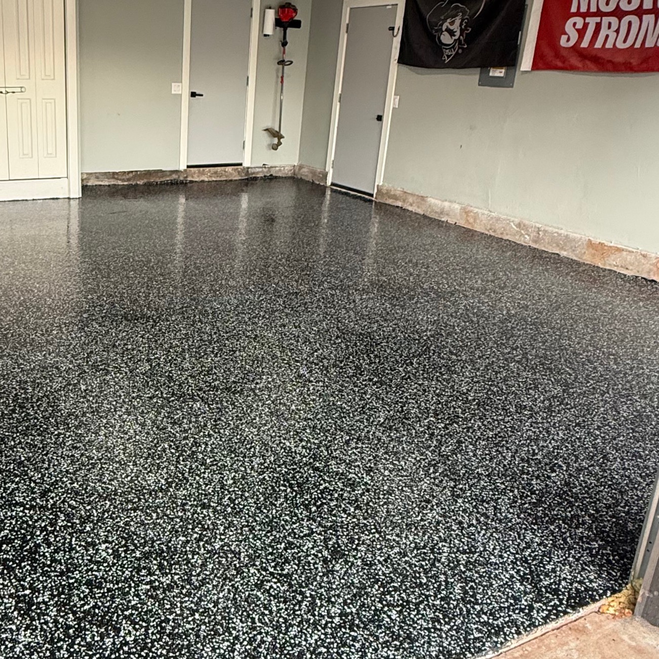 Ceiling lights reflecting in the gloss of a polyaspartic topcoat on a flake garage floor